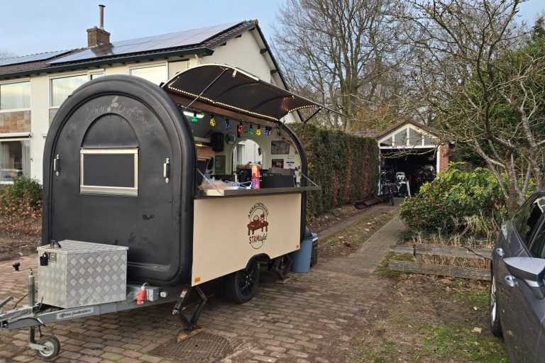 Zwart-wit afbeelding vanSTAMtafel foodtruck op een binnenplaats tussen appartementen.