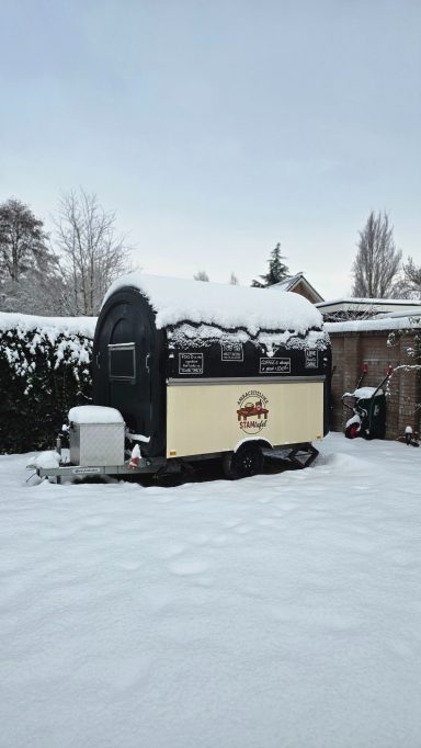 Een huisje bedekt met sneeuw in een besneeuwde omgeving.
