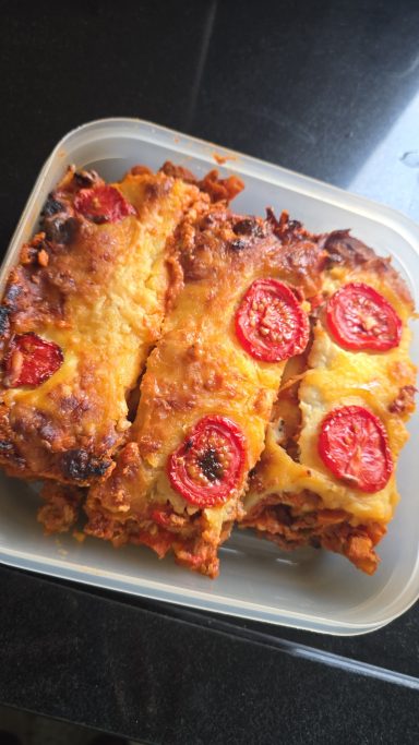 Gelaagd gerecht met tomaat, kaas en kruiden in een doorzichtige schaal.