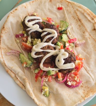 Wrap met gehaktballen, groenten en een romige saus.